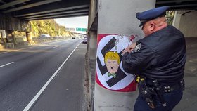 Policista odstraňuje hanlivý plakát s Trumpem, kde je boháč vyobrazen jako Hitler.