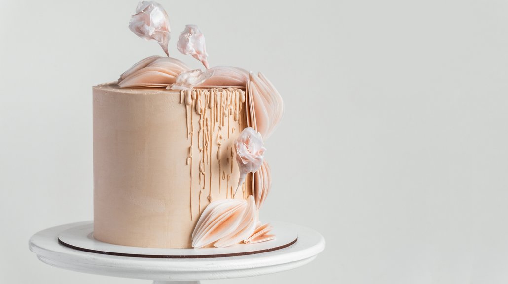 Tón v tónu. Krásný velký dort s béžovou čokoládovou polevou zdobený jedlými cukrovými květy a jedlým papírovým dekorem.