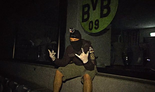 Maskovaný muž pózuje o loga Dortmundu nakreslené na stadionu Bayernu Mnichov.