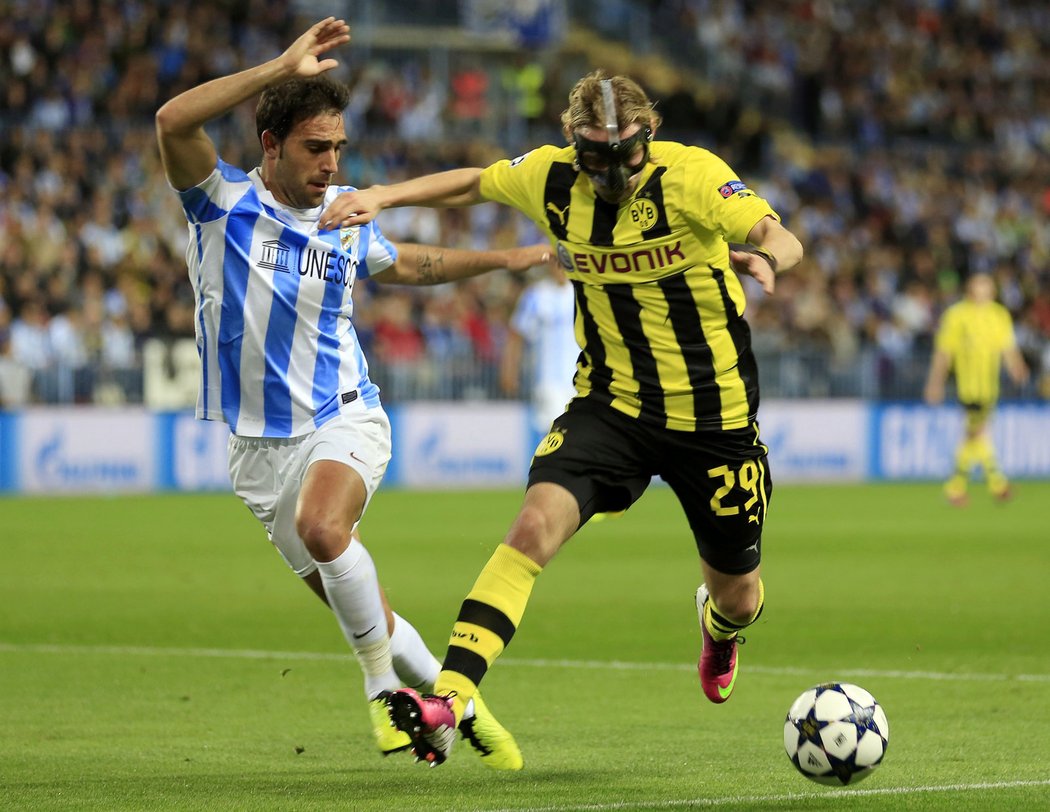 Obránce Dortmundu Marcel Schmelzer, který zápas odehrál s ochrannou maskou, udržel míč před atakujícím Jesusem Gamezem.