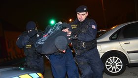 Policista odvádí jednoho z útočníků