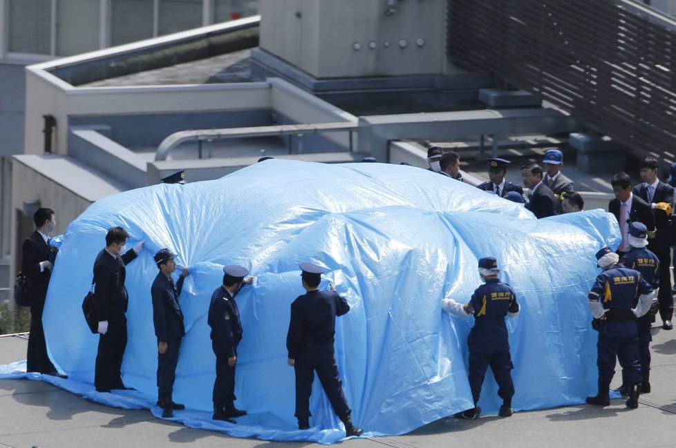 Policie přikrývá plachtou dron, který přistál na střeše u japonského premiéra.