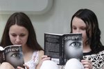 Dvě dívky (14 a 15) čtou novou knihu E. L. James.