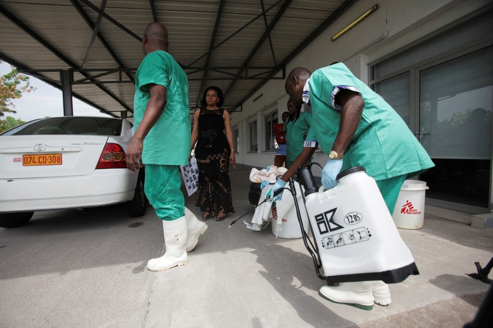Zdravotník sprejuje druhého dezinfekcí při přípravě na vyšetřování Eboly.