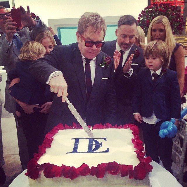 Elton John krájí dort. Po jeho levici je tříletý syn Zachary, vlevo 23 měsíční Elijah.