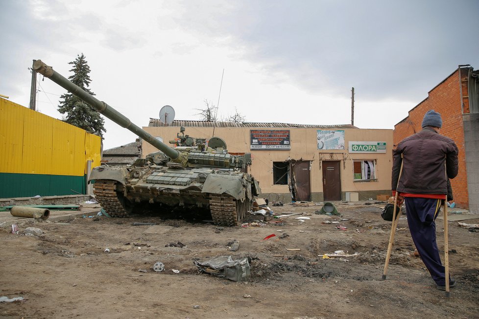 Místní obyvatel stojí vedle poškozeného ruského tanku T-72 (Trostjanec) 28.3.2022