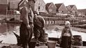 Dva rybáři a jejich malá pomocnice v tradičním oblečení a s dřeváky na nohou v nizozemském městečku Marken.