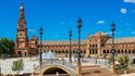 Plaza de España, Sevilla: Kuriózní původ má Plaza de España ve španělské Seville. V roce 1929 se měla v Seville konat velká Ibero-americká výstava. Za tímto účelem prošel jižní konec města markantní přestavbou. Hlavní roli v tomto procesu hrál proslulý park Marie Luisy na břehu řeky Guadalquivir, na jehož severní straně vyrostlo prostorné „Španělské náměstí“. Účelem tohoto projektu bylo vytvořit reprezentativní prostory, kde by se světu v rámci výstavy ukázaly poslední výdobytky španělského průmyslu a inovátorství. Výsledné náměstí je půlkruhem s fontánou uprostřed. Tento půlkruh ohraničuje vodní kanál, pro změnu obklopený půlkruhem okázalých budov, ve kterých se mísí architektonické prvky renesančního, barokního a maurského slohu.