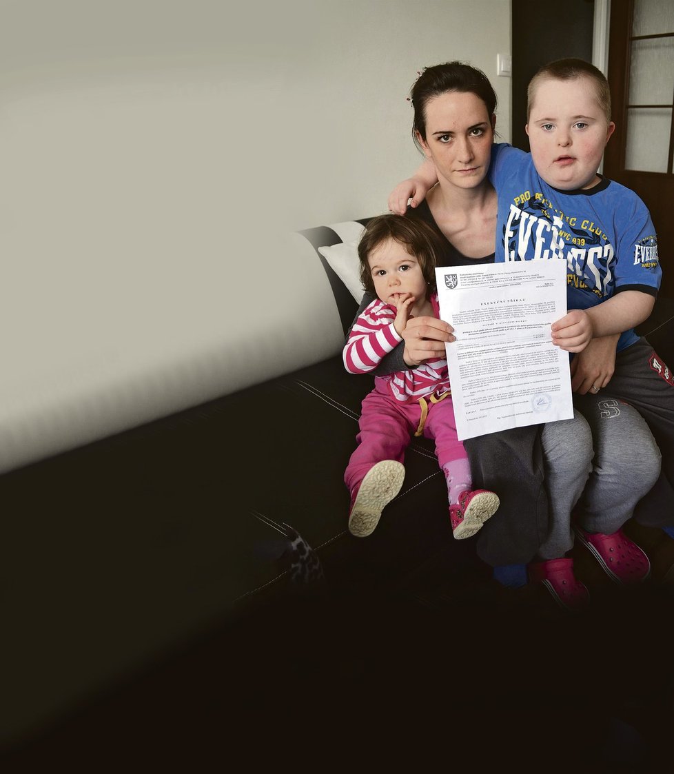 Romana Sládková (25) ukazuje exekuční příkaz. Na klíně má dceru Michalku (14 měsíců) a postiženého bratra Michala (7).