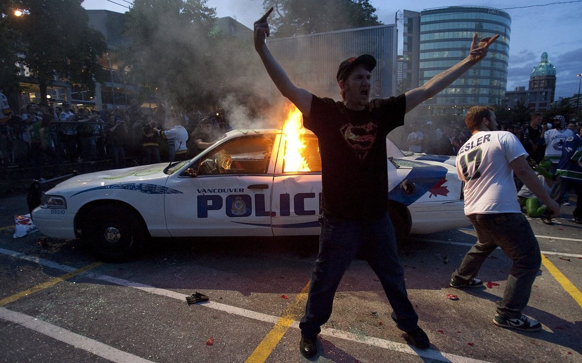 Revolta. Fanoušci oslavují plameny na policejním voze.