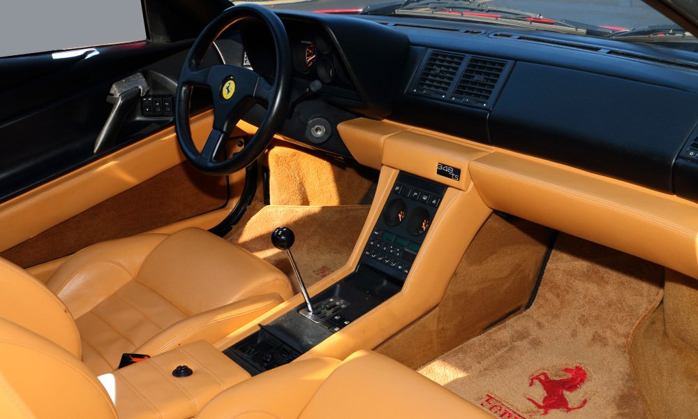 Interiér vozu Ferrari 348 TS v dvoubarevném provedení s koženými sedadly a řadicí pákou na středovém tunelu.