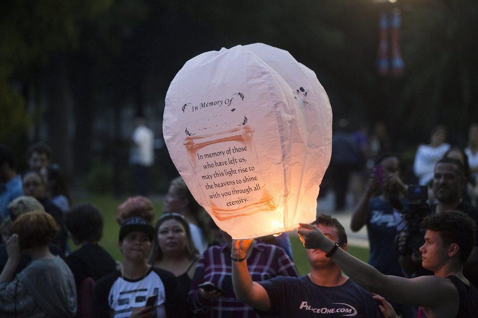 Lidé, často vybavení duhovými vlajkami, uctívají památku obětí.