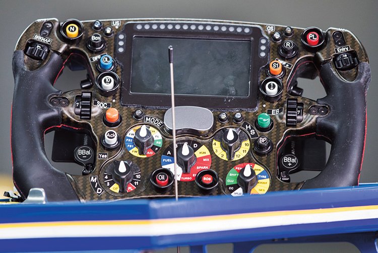 Volant F1 s tlačítky pro různá nastavení motoru, aktivaci pití, komunikaci s týmem apod.