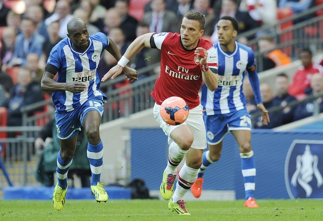 Útočník Arsenalu Lukac Podolski uniká hráčům Wiganu, ke gólu ale jeho sólo nevedlo