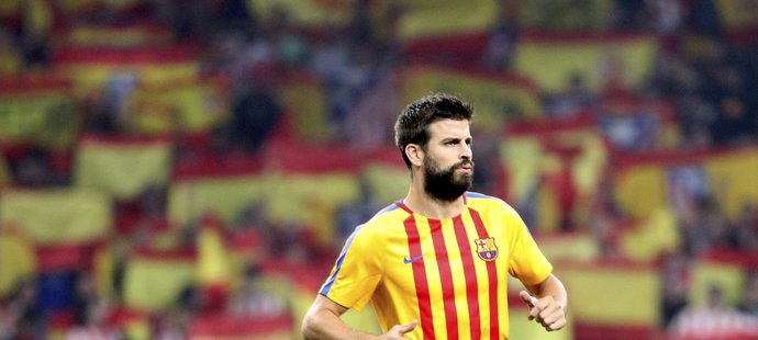 Obránce Barcelony Gerard Piqué při rozcvičení v katalánském dresu svého týmu. Za ním záplava španělských vlajek na tribunách stadionu Atlética.