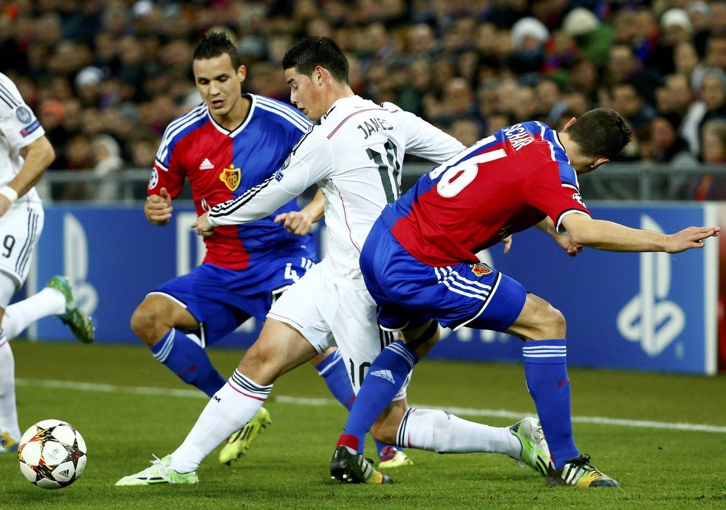 Záložník Realu Madrid James Rodríguez proniká mezi dvěma hráči Basileje