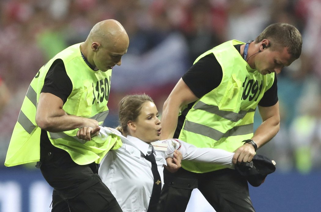 Pořadatelé odvádějí jednu z osob, která se dostala na hřiště při finále MS