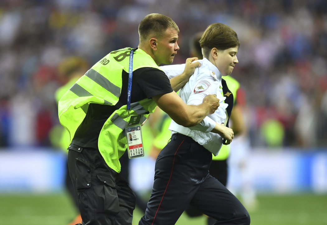 Pořadatelé odvádějí jednu z osob, která se dostala na hřiště při finále MS