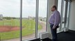 Předseda FAČR Miroslav Pelta se dívá z kanceláře na stadion Přátelství s fotbalovým hřištěm a atletickou dráhou