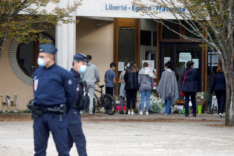 Lidé přinášejí květiny před budovu školy Collège du Bois d&#39;Aulne na pařížském předměstí, kde působil zavražděný učitel dějepisu (17. 10. 2020)