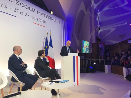 Francouzský prezident představil reformu povinné školní docházky. Promluvil také psychiatr Boris Cyrulnik (u pultíku), Macrona doprovázel jeho poradce, právník Jean-Michel Blanquer (zcela vlevo).