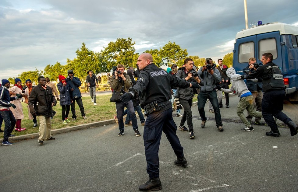 Nelegální imigranti se snaží dostat z Francie do Velké Británie. Policisté se je snaží zadržet.