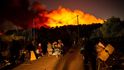 Lidé utíkají před plameny poté, co 9. září 2020 vypukl v táboře migrantů Moria na řeckém ostrově Lesbos velký požár