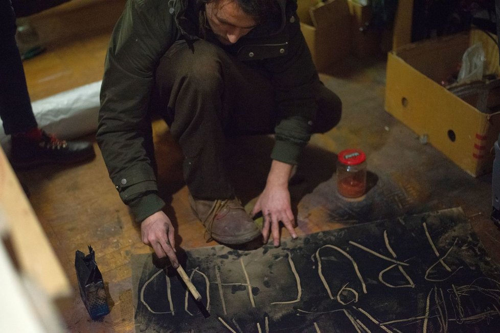 Adam Smolek vyrábí tabuli s nápisem Galerie Průchod.