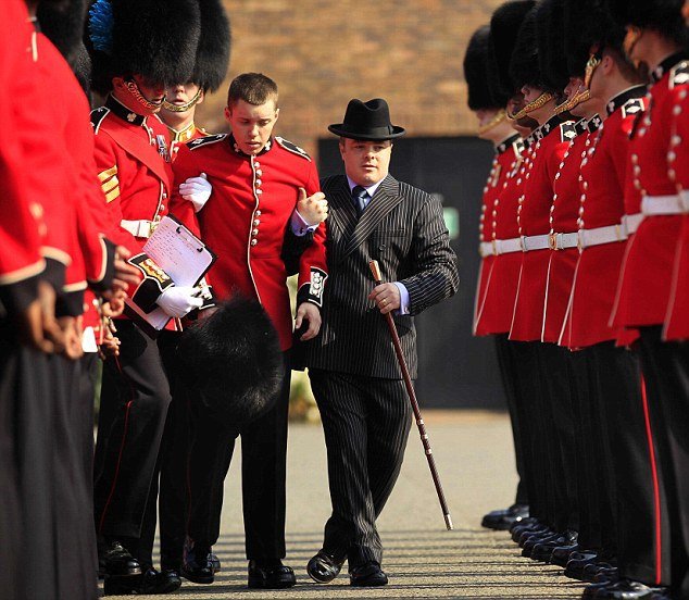 Vyčerpaný gardista, který se zhroutil během nácviku ceremonie, je odváděn k posádkovému lékaři.