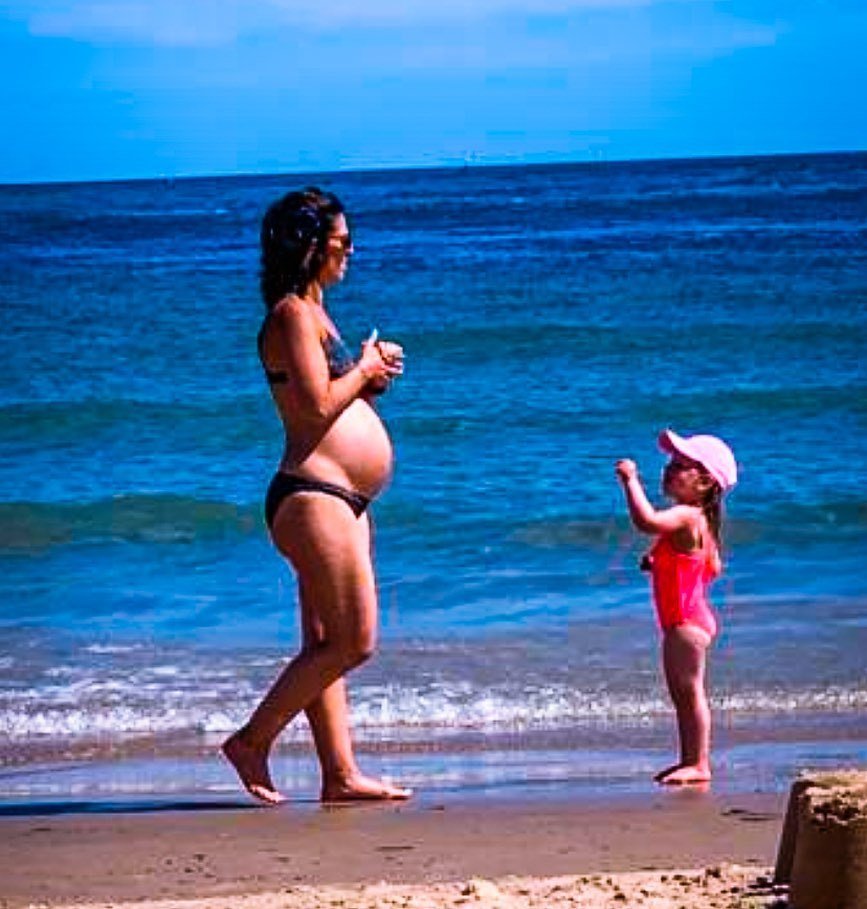 Gemma Isaacsová v těhotenství na pláži s dcerkou.