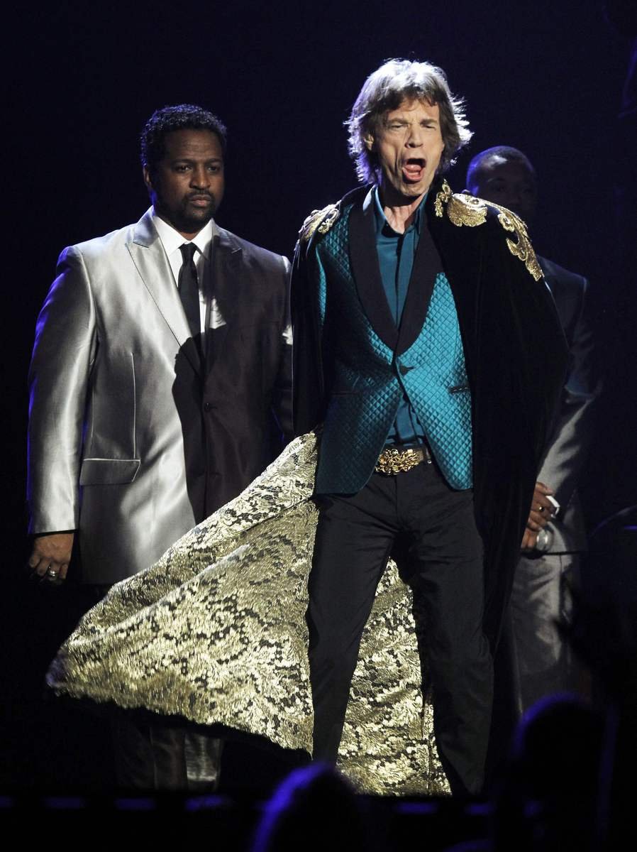 Mick Jagger. Sedmašedesátiletý Sir Michael Philips Jagger zůstal věrný klasickému stylu jedinečné britské extravagance. Černou skombinoval s petrol tyrkysem, sako oživil trochou saténového lesku plus šálovým límcem a prošíváním hodných županu...