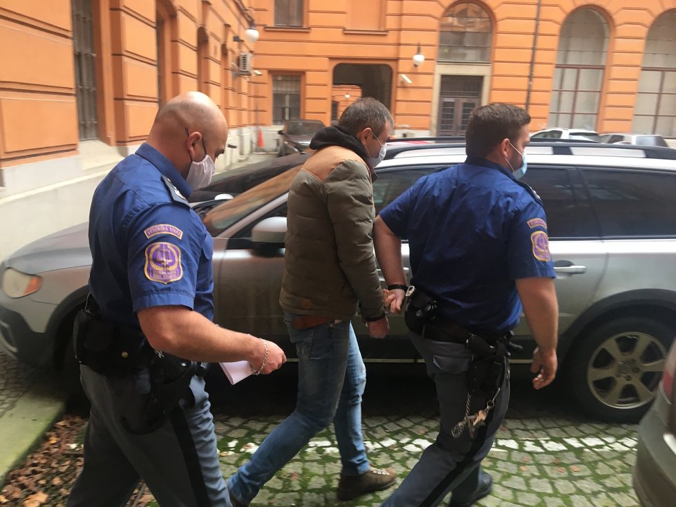 Eskorta odvádí od krajského soudu v Brně Gruzince Giorgi K. (31). Chtěl ukrást cukrovinky za 331 korun, pořezal přitom nožem do obličeje prodavačku, která mu v krádeži bránila.