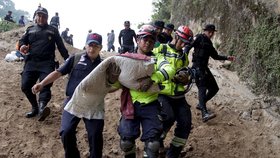 Záchranné týmy vynášejí těla obětí sesuvu půdy v Guatemale. Stovky záchranářů se snaží najít pohřešované.