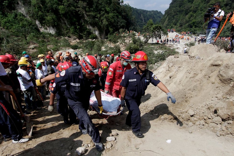 Záchranné týmy vynášejí těla obětí sesuvu půdy v Guatemale. Stovky záchranářů se snaží najít pohřešované.