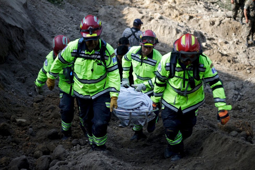 Záchranné týmy vynášejí těla obětí sesuvu půdy v Guatemale. Stovky záchranářů se snaží najít pohřešované.