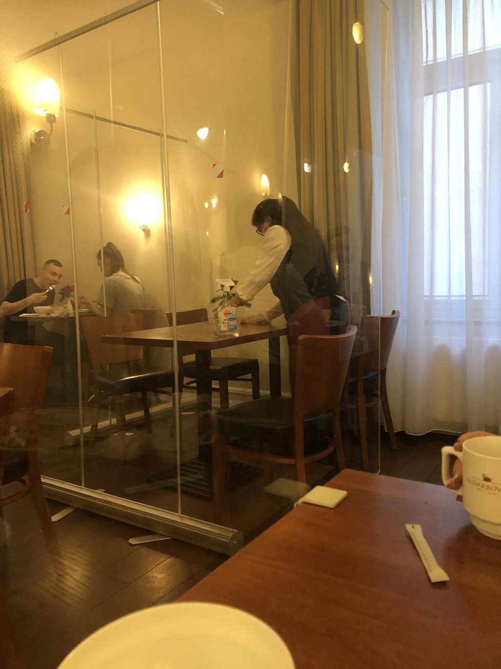 Stoly v hotelové restauraci oddělené plexiskly
