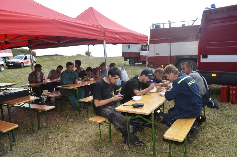 Provizorní zázemí pro hasiče vyrostlo na poli u lesa. Tady dostanou najíst a napít.