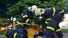 Když hasiči mříž kanálu odřezávali, kryli ženu i sebe před jiskrami létajícími z rozbrušovací pily.