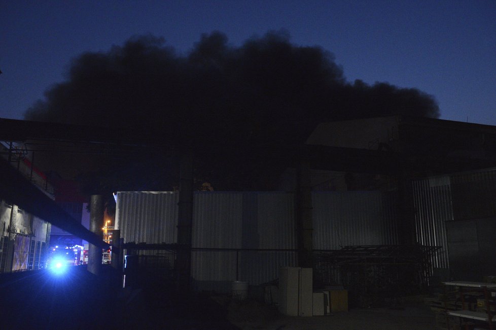 Hašení požáru továrny v pražských Vysočanech. Lidé přihlíželi, co se děje.