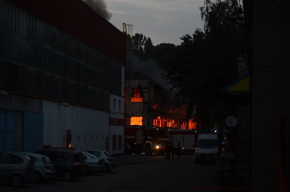 Hašení požáru továrny v pražských Vysočanech. Lidé přihlíželi, co se děje.