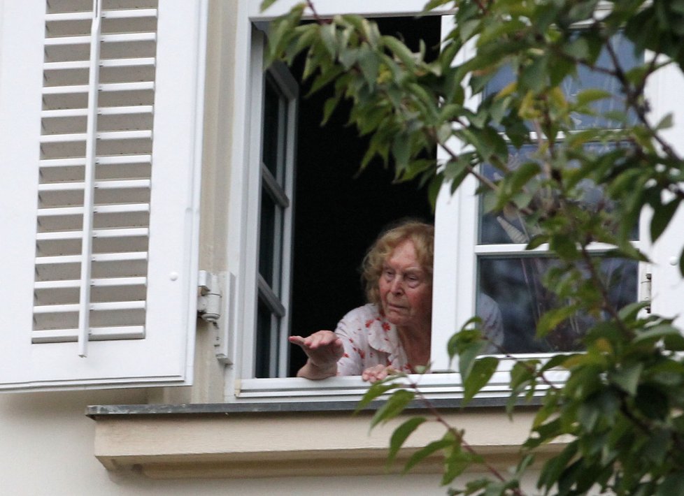 Markéta Veškrnová pozorovuje z okna dění před vilou