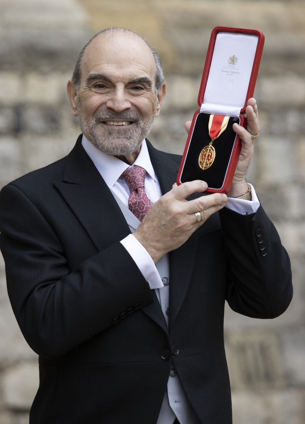 Hrdý sir David Suchet ukazuje právě obdržený řád.