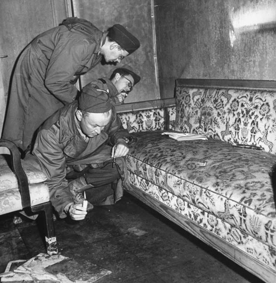 Váleční korespondenti prohlížejí gauč, na němž se Hitler zastřelil