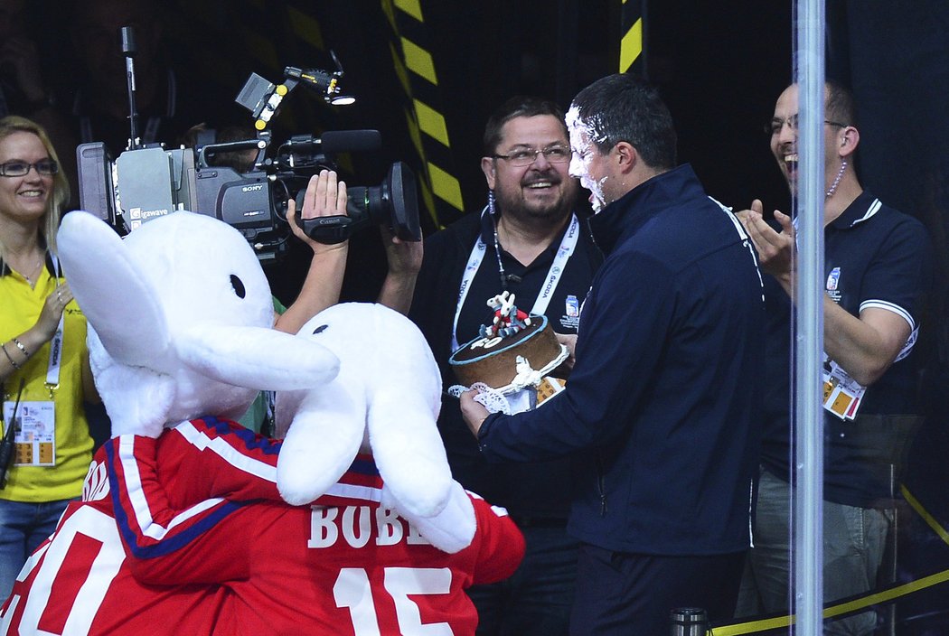Maskoti šampionátu Bob a Bobek sledují, jak  ředitel sportovního oddělení mistrovství světa Jan Černý dostal narozeninový dort