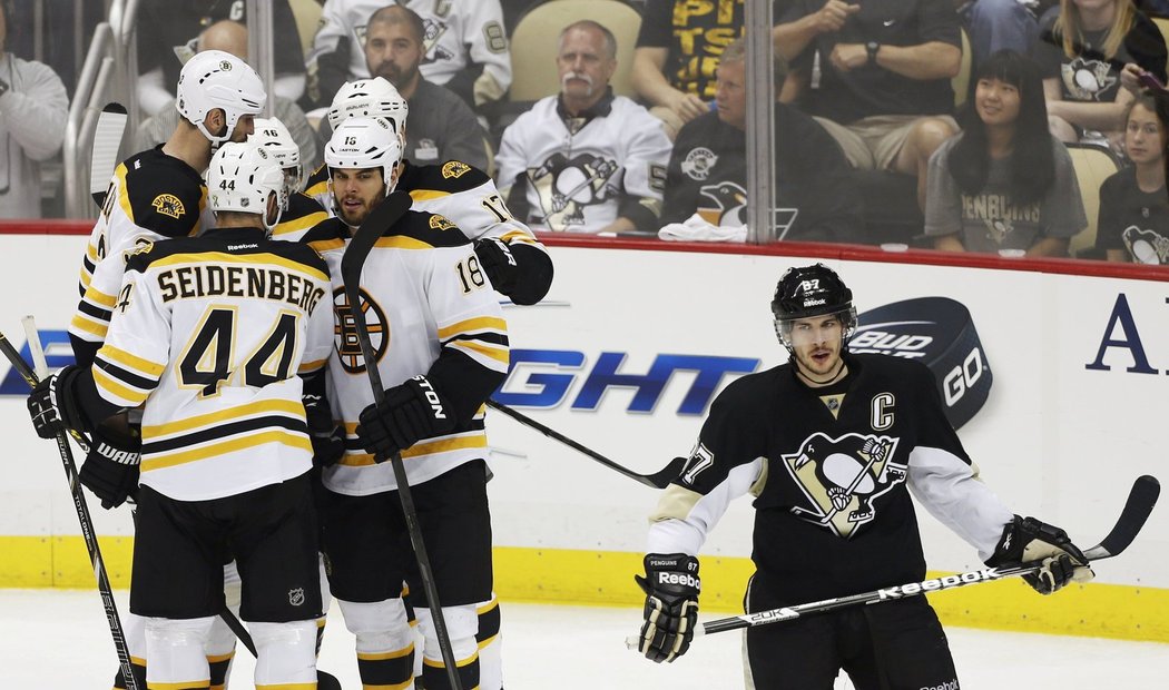 Hokejisté Bostonu slaví jeden z gólů v pittsburghské síti, kapitán domácích Sidney Crosby zklamaně odjíždí z ledu