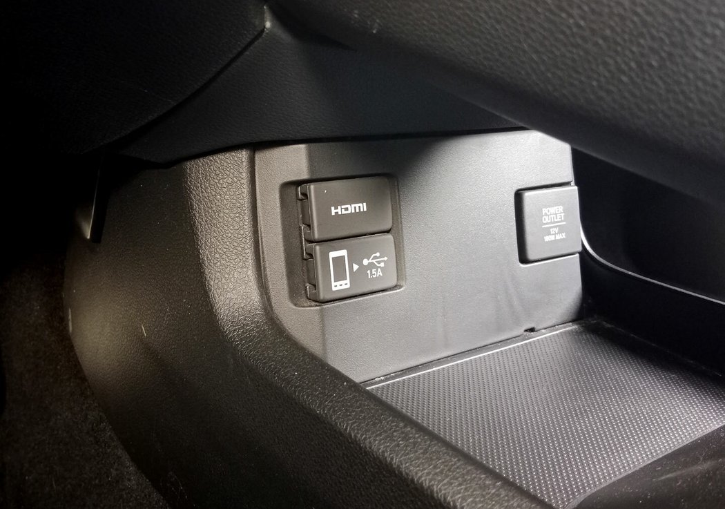 Hluboká šachta mezi sedadly je sice praktická, ale estetickému dojmu by hodně prospělo, kdyby šla celá zakrýt roletkou nebo delší loketní opěrkou. Port USB v šachtě slouží spíš pro lehčí přiživení baterie telefonu, pro Apple CarPlay nebo Android Auto se musíte kabelem připojit do portu USB nešikovně schovaného pod středovým tunelem.