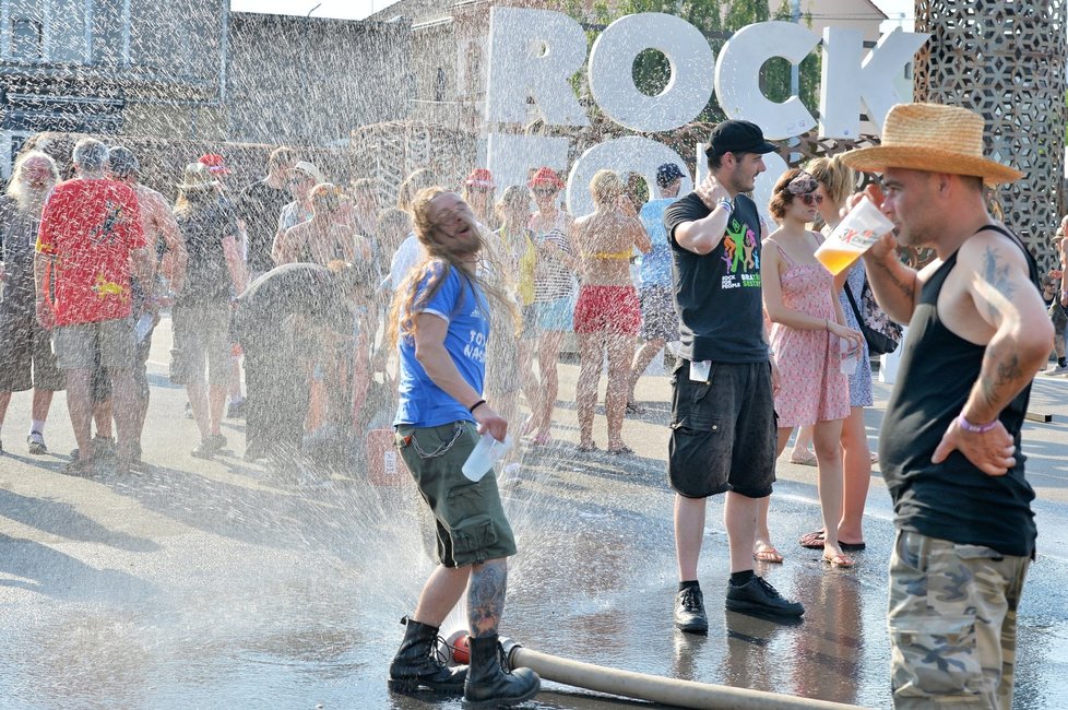 Návštěvníci festivalu Rock for People v Plzni se 4. července osvěžují vodou z hasičské hadice.