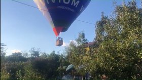 Modrý horkovzdušný balón míří na rodinný dům. Pilot podle rodiny minul střechu a komín doslova o fous.