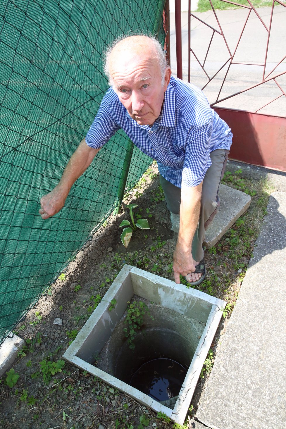 Václav Kuželka ukazuje vyústění kanalizační přípojky na svém pozemku.
