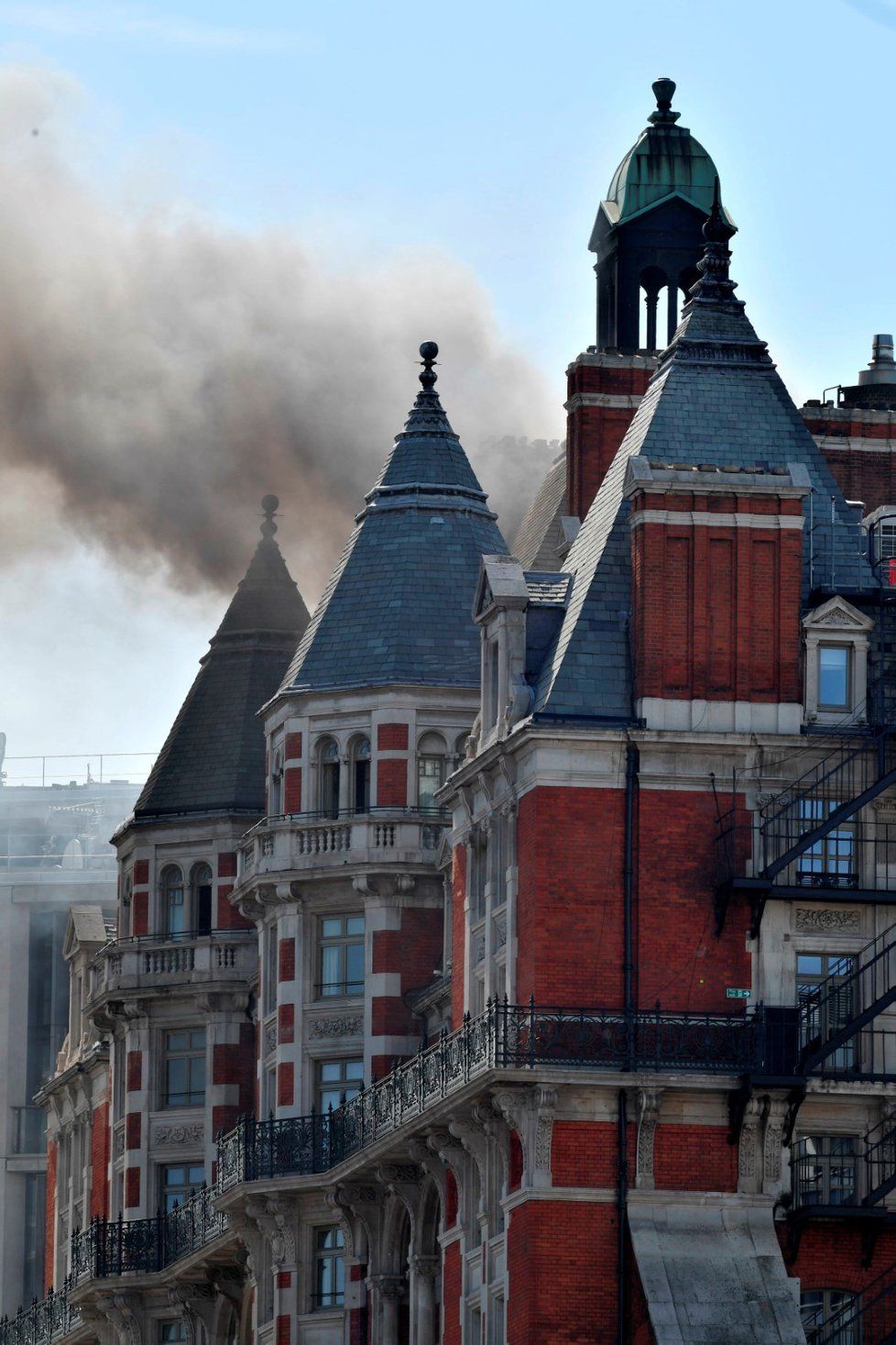 Více než stovka hasičů bojuje s požárem luxusního hotelu v centru Londýna. Ze střechy budovy stoupá hustý dým